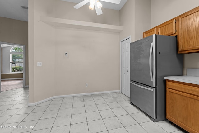 kitchen featuring baseboards, light tile patterned flooring, light countertops, and freestanding refrigerator