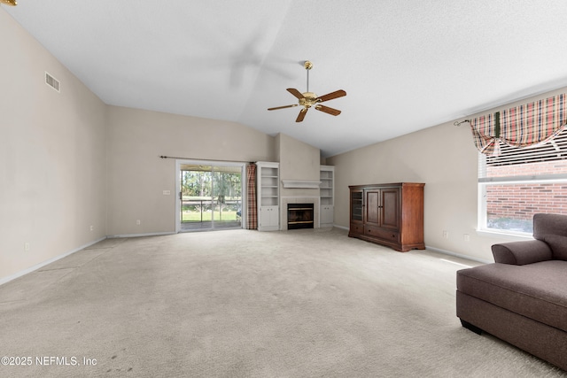 living area with visible vents, baseboards, light colored carpet, vaulted ceiling, and a fireplace