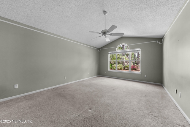 carpeted spare room with a textured ceiling, lofted ceiling, baseboards, and ceiling fan