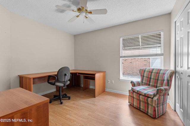 office space with baseboards, a textured ceiling, light wood-style floors, and a ceiling fan