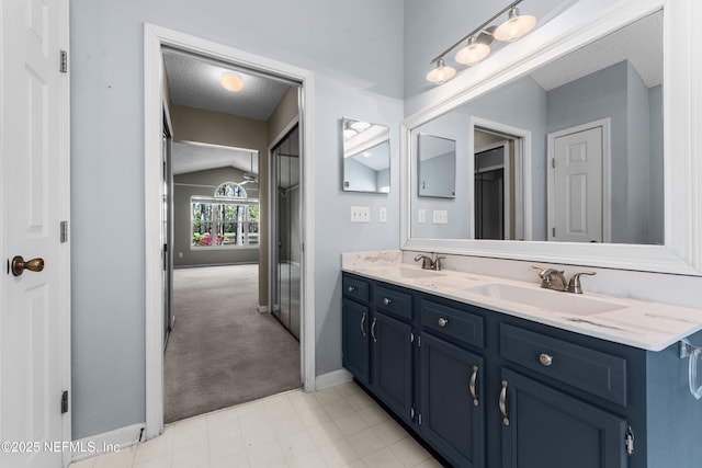 full bathroom featuring a textured ceiling, double vanity, lofted ceiling, and a sink