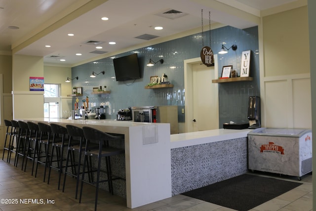 bar with a community bar, visible vents, tasteful backsplash, and a decorative wall