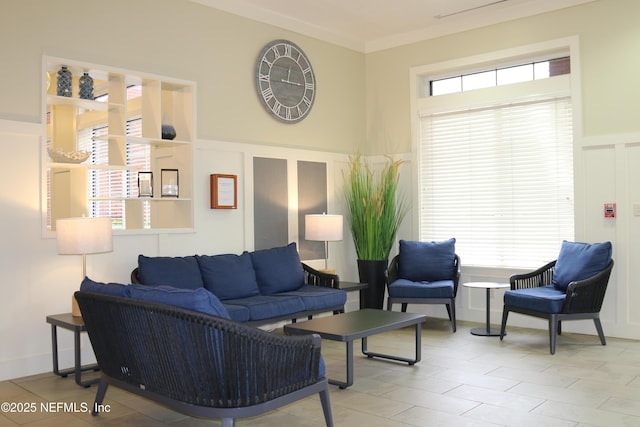 living area with light tile patterned flooring, ornamental molding, and a decorative wall