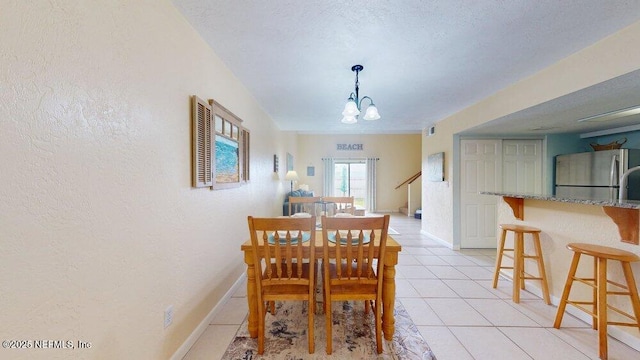 dining area with a textured ceiling, light tile patterned flooring, visible vents, baseboards, and an inviting chandelier