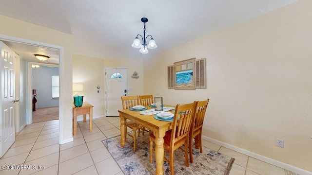 dining area featuring light tile patterned floors, an inviting chandelier, and baseboards