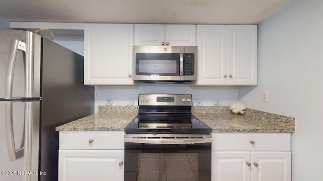 kitchen with light stone counters, appliances with stainless steel finishes, and white cabinetry