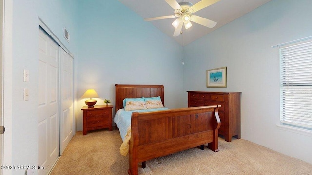 bedroom featuring a closet, light colored carpet, visible vents, a ceiling fan, and vaulted ceiling