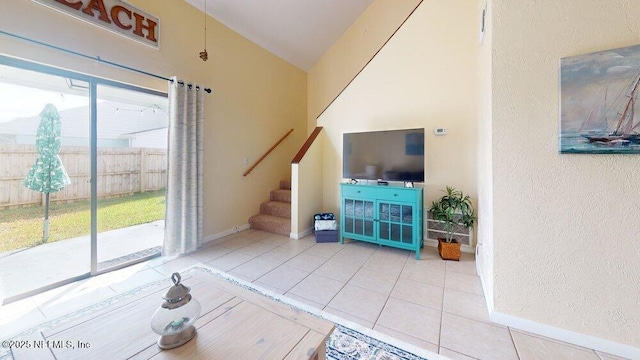 unfurnished living room with stairs, a textured wall, vaulted ceiling, baseboards, and tile patterned floors