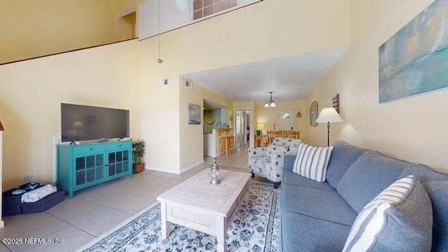 living area featuring baseboards, a towering ceiling, and tile patterned floors