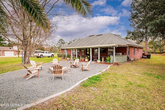 rear view of property featuring a yard, a fire pit, and a patio