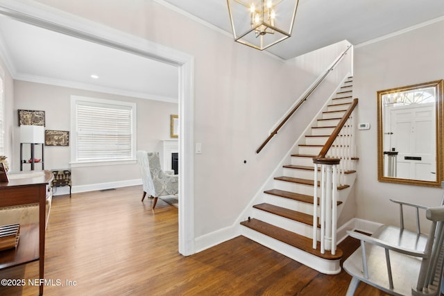 stairs featuring hardwood / wood-style flooring, crown molding, and an inviting chandelier