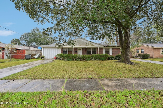 ranch-style house featuring a front yard, concrete driveway, brick siding, and fence