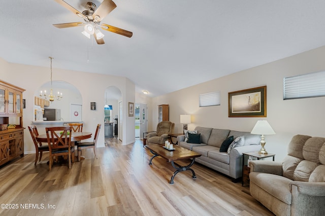 living room featuring ceiling fan with notable chandelier, light hardwood / wood-style flooring, and lofted ceiling