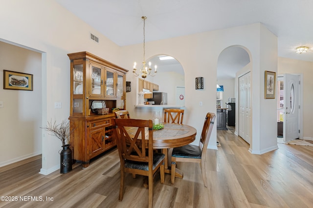 dining room featuring light wood-type flooring and a notable chandelier