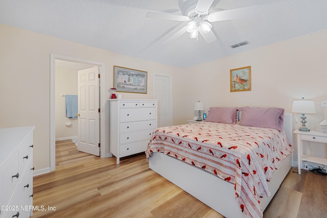 bedroom with ceiling fan, light hardwood / wood-style flooring, and a textured ceiling