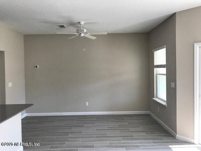 spare room with ceiling fan, a textured ceiling, visible vents, baseboards, and wood tiled floor