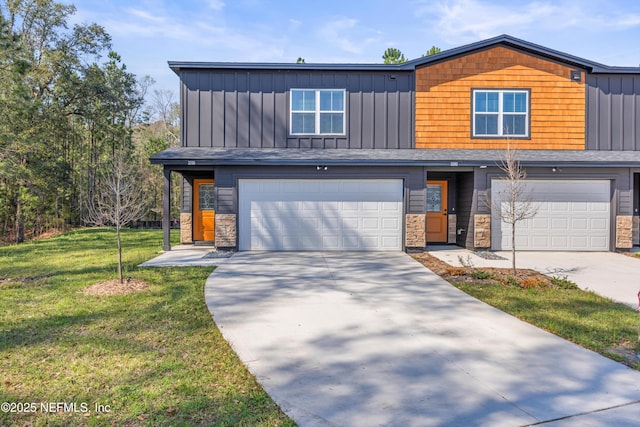 view of front of house with a garage, concrete driveway, board and batten siding, and a front yard