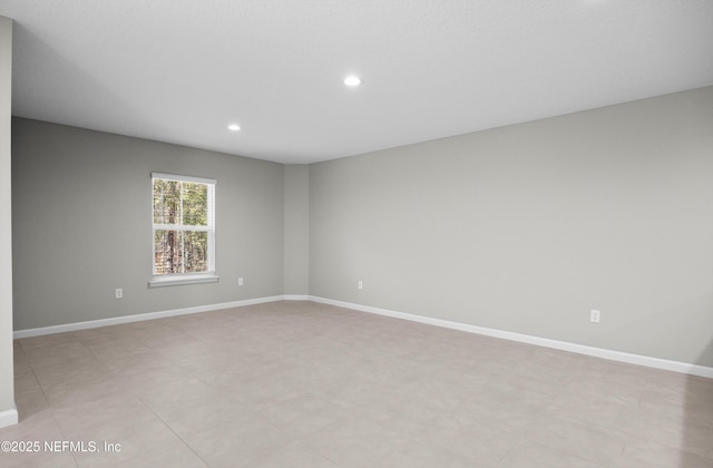 spare room featuring recessed lighting and baseboards