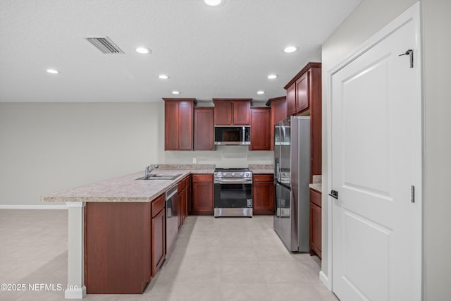 kitchen with light countertops, visible vents, appliances with stainless steel finishes, a sink, and a peninsula