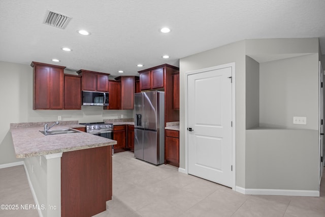 kitchen with reddish brown cabinets, visible vents, appliances with stainless steel finishes, a peninsula, and a sink