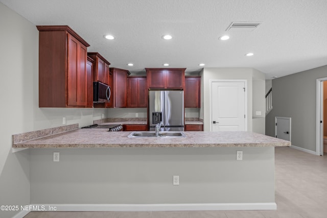 kitchen with visible vents, stainless steel appliances, dark brown cabinets, light countertops, and a sink