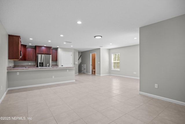 unfurnished living room featuring light tile patterned floors, recessed lighting, and baseboards