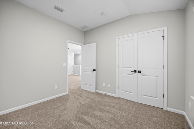 unfurnished bedroom with lofted ceiling, baseboards, visible vents, and carpet flooring