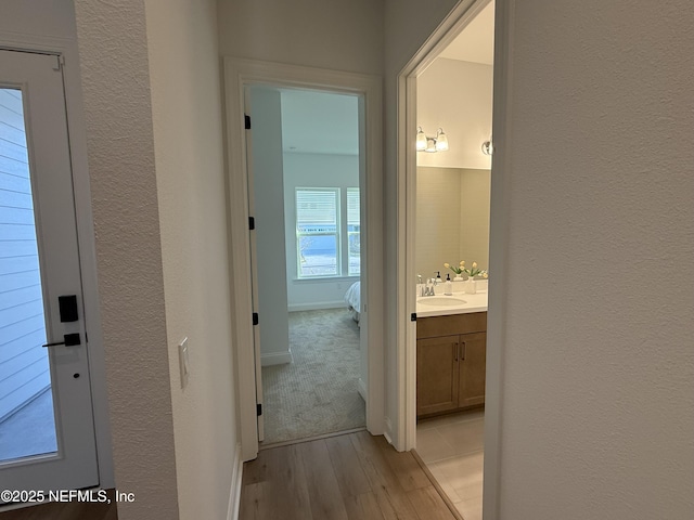 hallway with light hardwood / wood-style flooring and sink