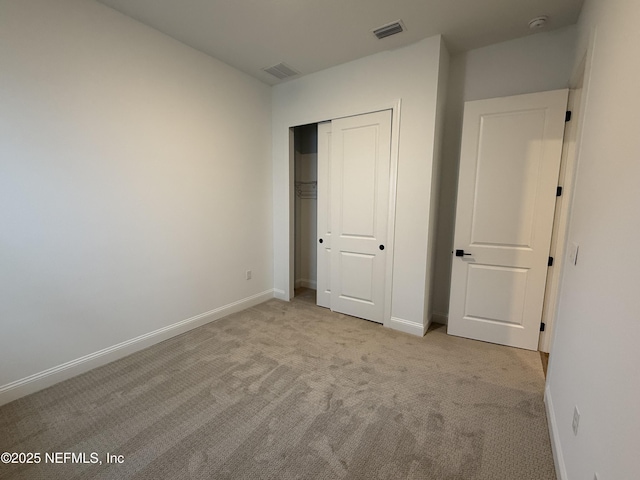 unfurnished bedroom with a closet and light colored carpet