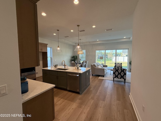 kitchen featuring light hardwood / wood-style flooring, sink, dishwasher, hanging light fixtures, and a kitchen island with sink