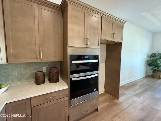 kitchen with double oven, light wood-type flooring, and tasteful backsplash