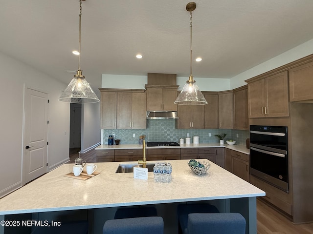 kitchen with hanging light fixtures, sink, and a kitchen island with sink