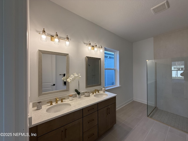 bathroom with vanity, a tile shower, and a textured ceiling