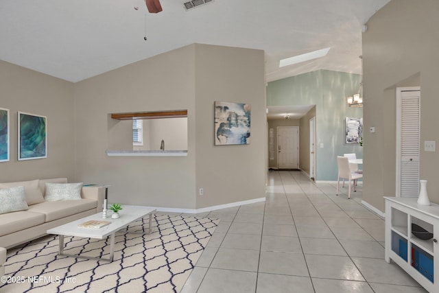 tiled living room featuring ceiling fan with notable chandelier and vaulted ceiling