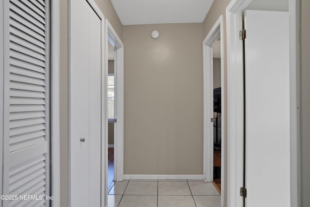 corridor featuring a textured ceiling and light tile patterned flooring