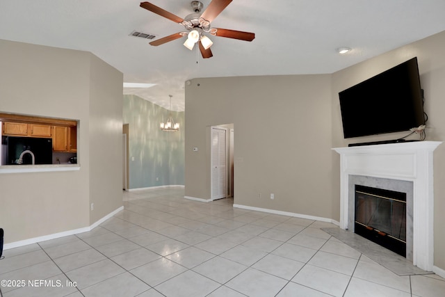 unfurnished living room with light tile patterned flooring, vaulted ceiling, ceiling fan with notable chandelier, and a high end fireplace