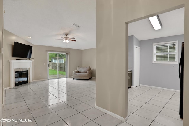 unfurnished living room with lofted ceiling, light tile patterned floors, a fireplace, and ceiling fan