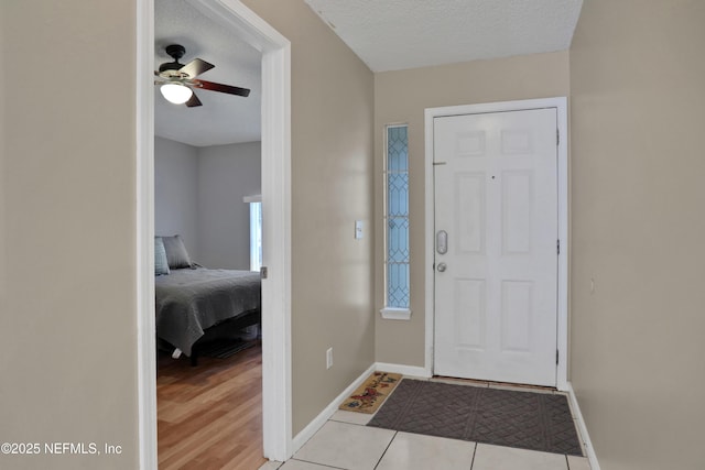 entrance foyer with light tile patterned flooring, ceiling fan, and a textured ceiling