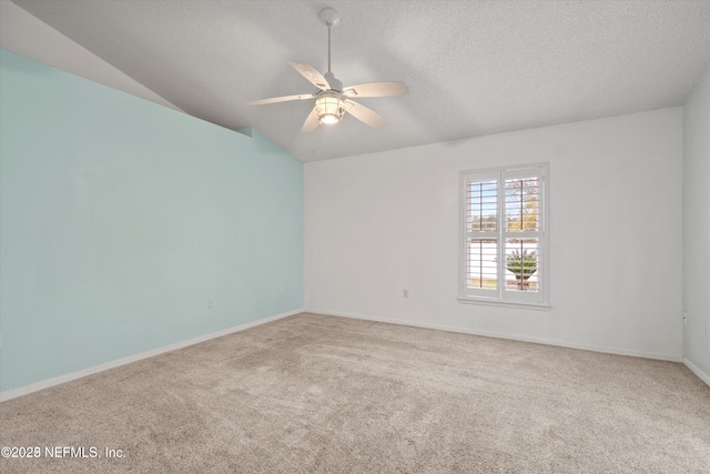 unfurnished room featuring carpet, baseboards, ceiling fan, vaulted ceiling, and a textured ceiling