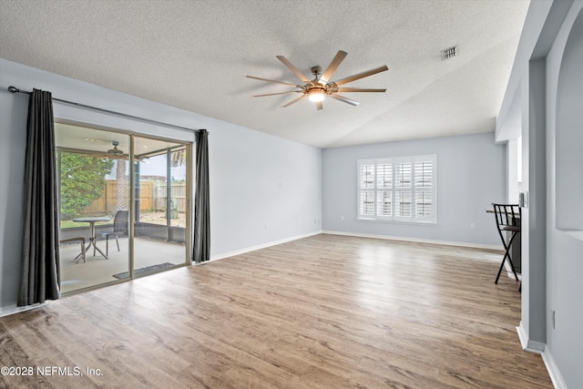 unfurnished living room featuring wood finished floors, baseboards, visible vents, lofted ceiling, and ceiling fan