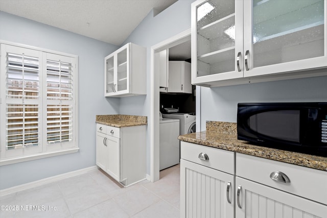 kitchen featuring light tile patterned floors, glass insert cabinets, black microwave, white cabinetry, and independent washer and dryer