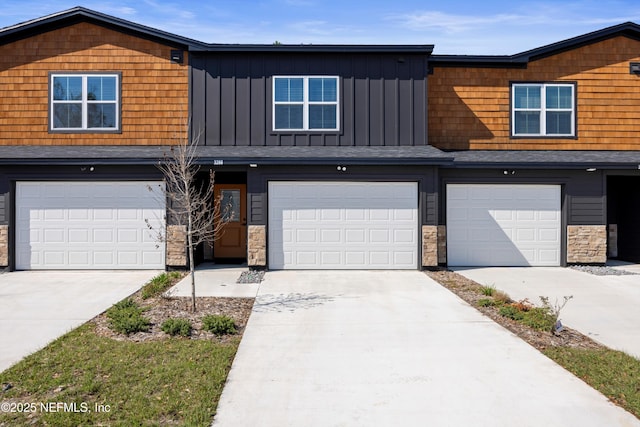 view of front of house with a garage, stone siding, board and batten siding, and concrete driveway