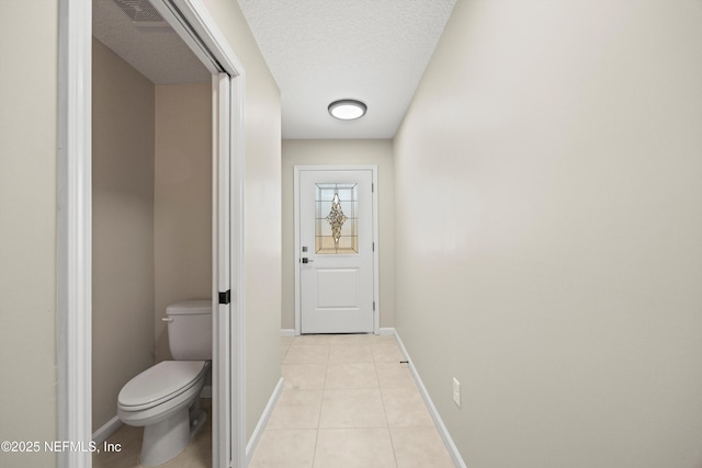 doorway to outside with light tile patterned floors, baseboards, visible vents, and a textured ceiling