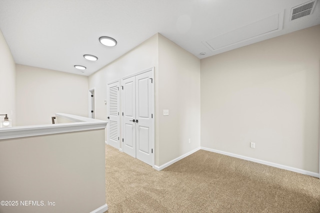 hallway with carpet floors, visible vents, and baseboards