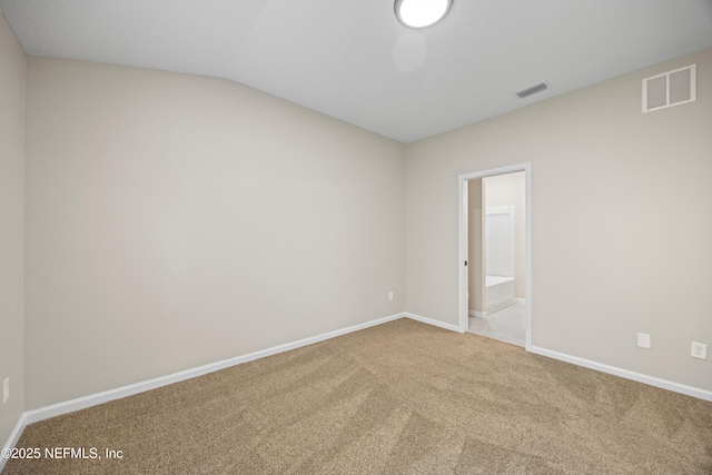 empty room with carpet, visible vents, lofted ceiling, and baseboards