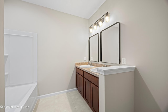 full bathroom with double vanity, baseboards, tile patterned flooring, a bathtub, and a sink