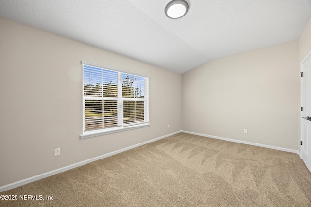 spare room featuring lofted ceiling, a textured ceiling, carpet flooring, and baseboards