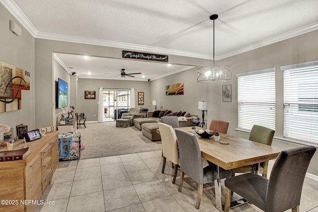 dining area featuring light tile patterned flooring, ceiling fan, crown molding, and a textured ceiling