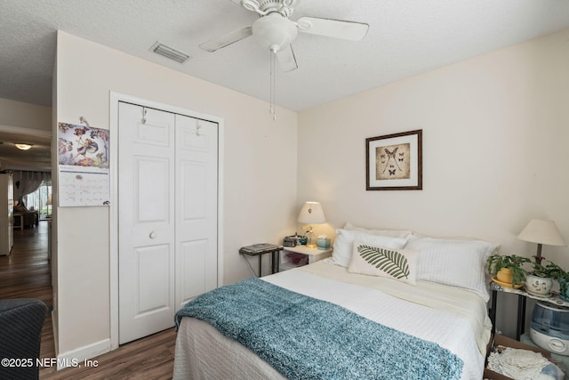 bedroom featuring a textured ceiling, dark wood-type flooring, ceiling fan, and a closet