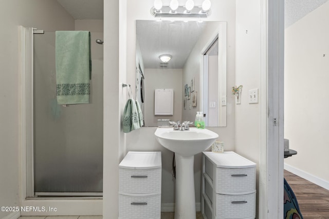 bathroom with an enclosed shower, a textured ceiling, and hardwood / wood-style floors